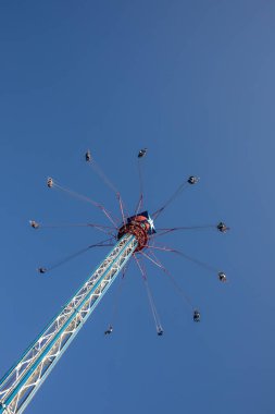 Bir lunaparkta mavi gökyüzüne karşı yüksek irtifada salıncak..