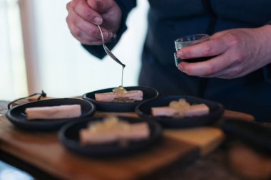 Şef modern bir mutfakta gurme aperatifleri kaşıkla süslüyor.