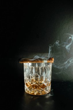 Rocks Glass of whiskey with a smoking cigar clipart