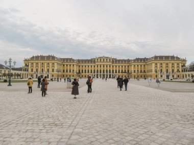 Geniş bir avlusu olan tarihi bir sarayın önündeki insanlar.