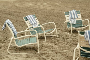 Kumlu sahilde çizgili havlular ve plaj sandalyeleri