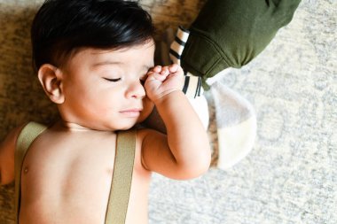 Baby peacefully sleeping on a soft surface with a stuffed toy be clipart