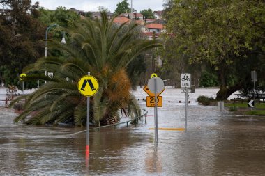 Flooded street with road signs after Maribyrnong River floods clipart