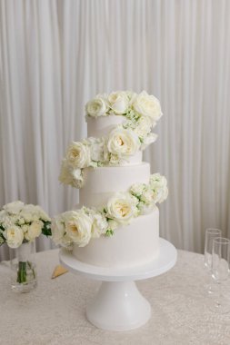 Beyaz katlı düğün pastası ve beyaz güller