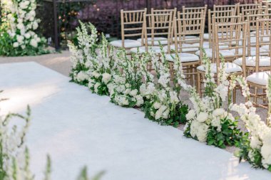 Beyaz koridor koşucusu ve çiçekçiler açık hava düğün töreninde