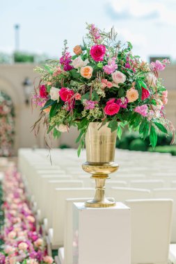 Güneşli bir günde, açık havada yapılan düğün töreninde altın vazodaki çiçekler.