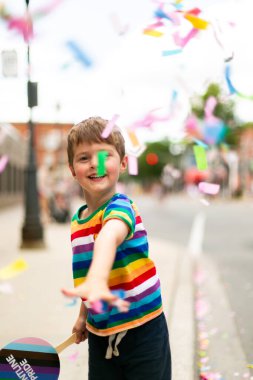 Çocuk onur yürüyüşüne konfeti fırlatıyor.