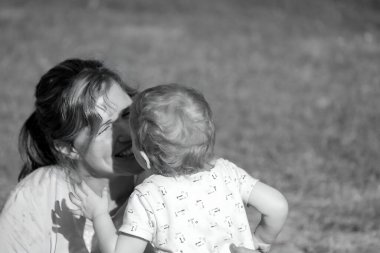 Mother and baby sharing a close moment outdoors, black and white