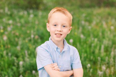 Mavi elbiseli genç kır çiçekleri arasında gülümsüyor.