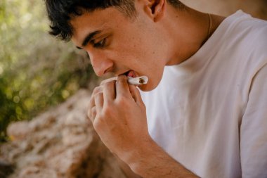 Açık havada marihuana içen bir çocuğun yakın çekimi.