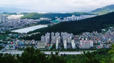 Yüksek binaları ve dağları olan bir Kore şehrinin havadan görünüşü