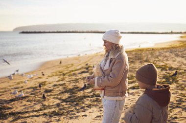 mother and her son giving bread to seagulls. clipart