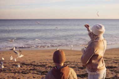 Anne ve oğlu martılara ekmek veriyor..