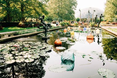 Colorful Chihuly Glass Sculptures Floating in Pond at Botanical Garden clipart