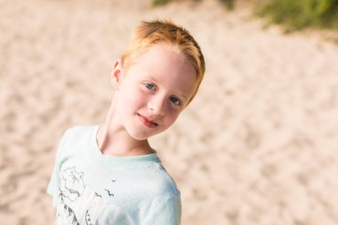 Yüzünde kırıntılar olan sahildeki küçük çocuk.