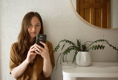 Kadın en az iç mekanda otururken telefonda kayar