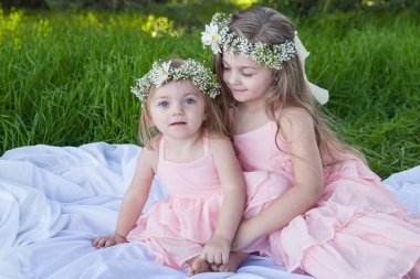 Pembe elbiseli rahibeler güneşli bir çayırda sevgi dolu bir anı paylaşıyorlar.