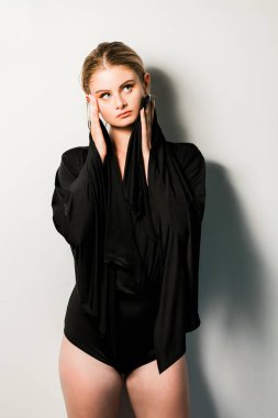 Siyah tayt içinde meraklı görünen genç bir kadının stüdyo portresi.