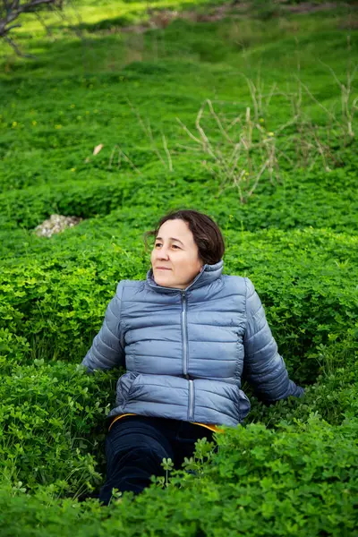 Stock image woman in grey jacket sitting on green grass