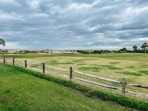 stock image Vast open field of green with rustic wooden fence on a cloudy day