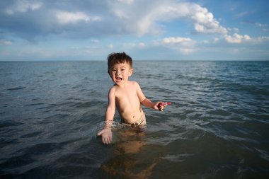 Bir çocuk suda durur ve güler, gün batımı, yaz vadisi