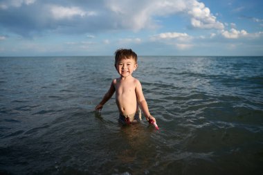 Bir çocuk suda durur ve güler, gün batımı, yaz vadisi