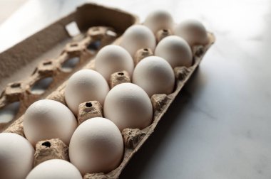 Mermer tezgahtaki bir düzine beyaz yumurtanın açılı görüntüsünü kapat..