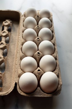 Mermer tezgahtaki bir kutu beyaz yumurtanın yakın görüntüsü.