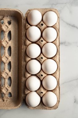 Tepede mermer tezgahta bir düzine beyaz yumurta var..