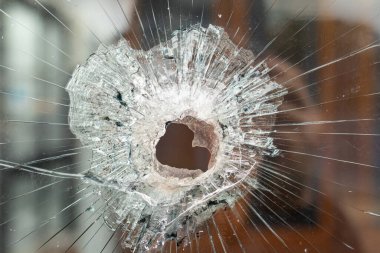 Parçalanmış camlara yakın çekim ve merkezi bir mermi deliği darbesi.