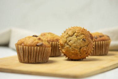 Kesme tahtasındaki dört muffin bir kekin tepesini gösteriyor.