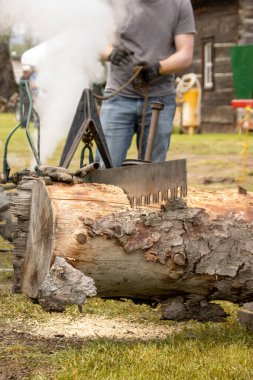 Antika kereste fabrikası işleten adam buhar gücüyle kütük kesiyor.