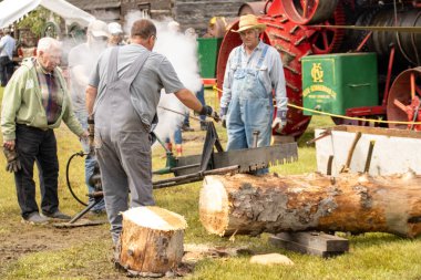 Dışarıdaki bir etkinlikte kereste kesmek için buharlı kereste fabrikası kullanan adamlar.