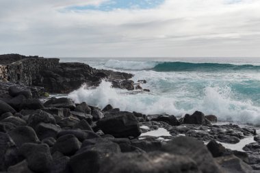 Okyanus dalgaları Kailua-Kona 'da deniz kenarındaki siyah lav kayalarına çarpar..