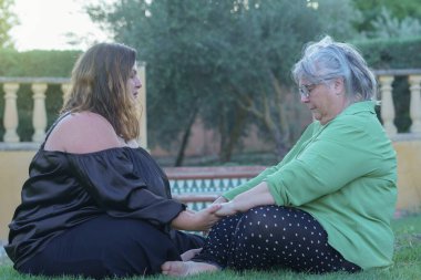 İki kadın el ele tutuşup meditasyona konsantre oluyor.