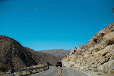 Dönen bir çöl yolunda araba sürüyor..