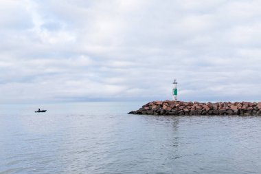 Indiana Dunes 'da kayalık bir rıhtımda deniz feneri ve uzak bir tekne.