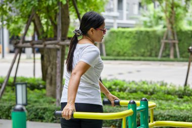 Halk parkında Eliptik üzerinde egzersiz yapan Asyalı kadın.