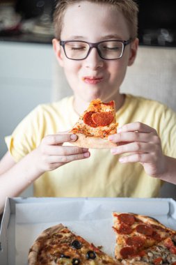 Paketten pizza yiyen hoş bir genç çocuk.