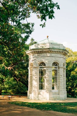 Güneşli bir günde, yemyeşil bir parktaki taş çardak.