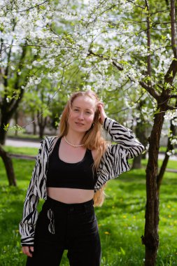 Baharda çiçek açan ağaçların yanında genç bir kadın