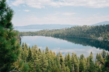 Dağlara ve gölden yansıyan bir ağaç hattına bakın.