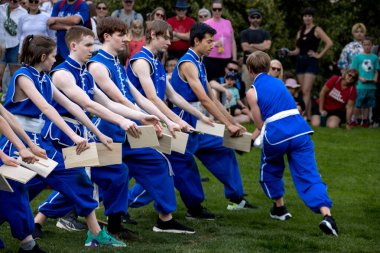 Group of kids demonstrating kung fu in blue uniforms outdoors clipart