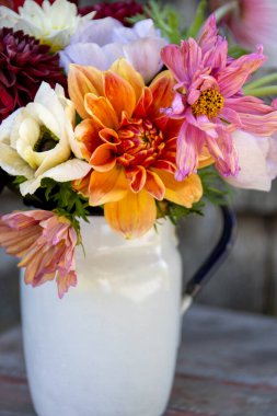 Beyaz bir sürahi içinde renkli bir çiçek buketinin yakın çekimi.
