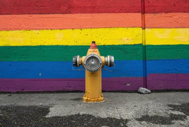 Fire hydrant in front of a colorful wall painted with rainbow colors clipart