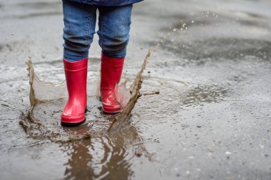 Yeni yürümeye başlayan çocuğun botlarının su birikintisine atlama sahnesi..