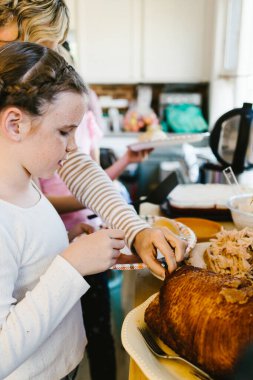 Şükran Günü 'nde aile mutfakta jambon ve hindi yer.