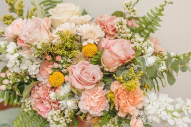 Pastel güller ve vazodaki eğreltiotu ile zarif bir çiçek düzenleme.