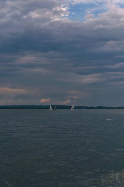 Bulutlu bir günde denizde yelkenliler.