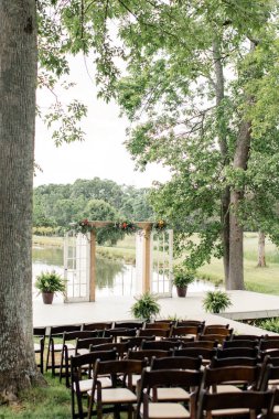 Göl kenarında bir kemer ve sandalyeli açık hava düğün töreni..